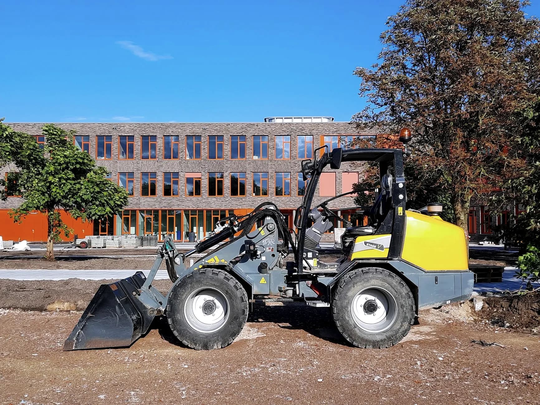 Compacte shovel met bak op een werf